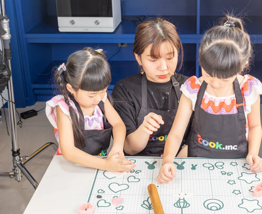 A chef showing two children how to shape dough
