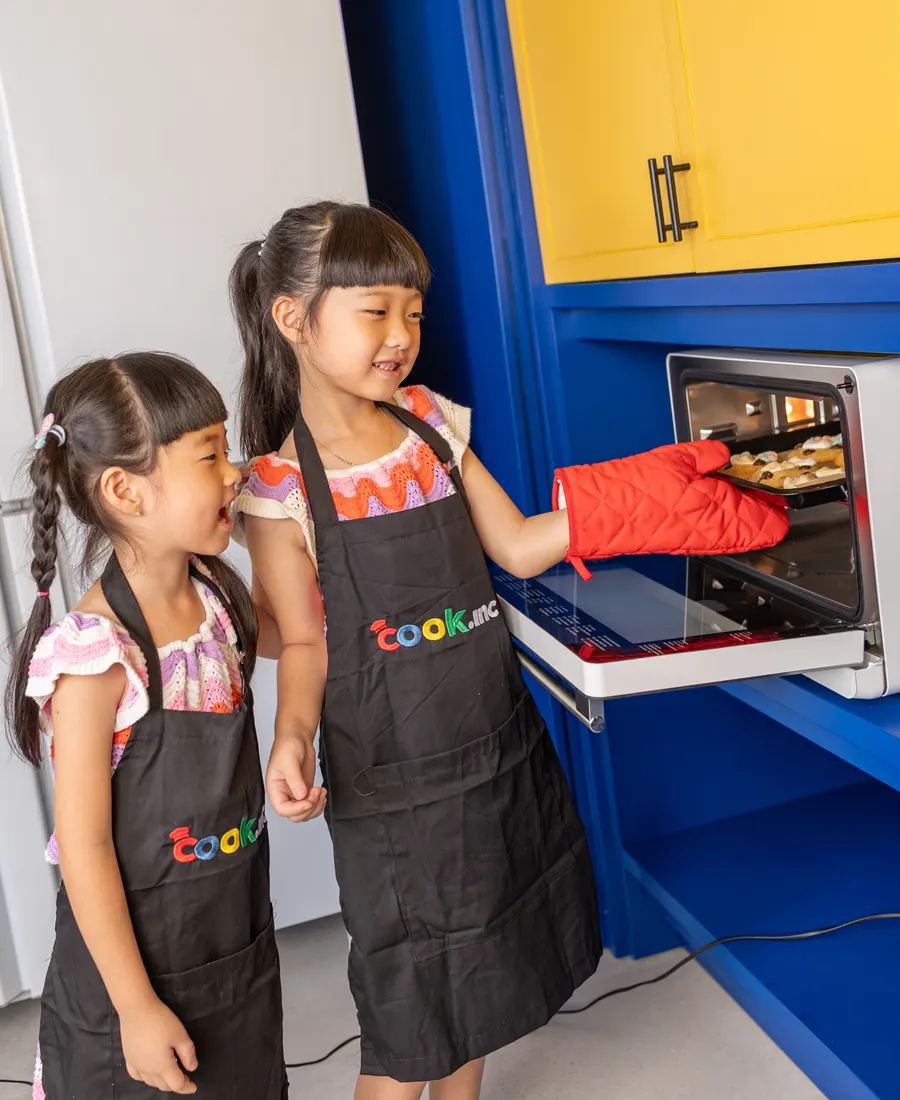 Children taking a tray out of the oven with mitts