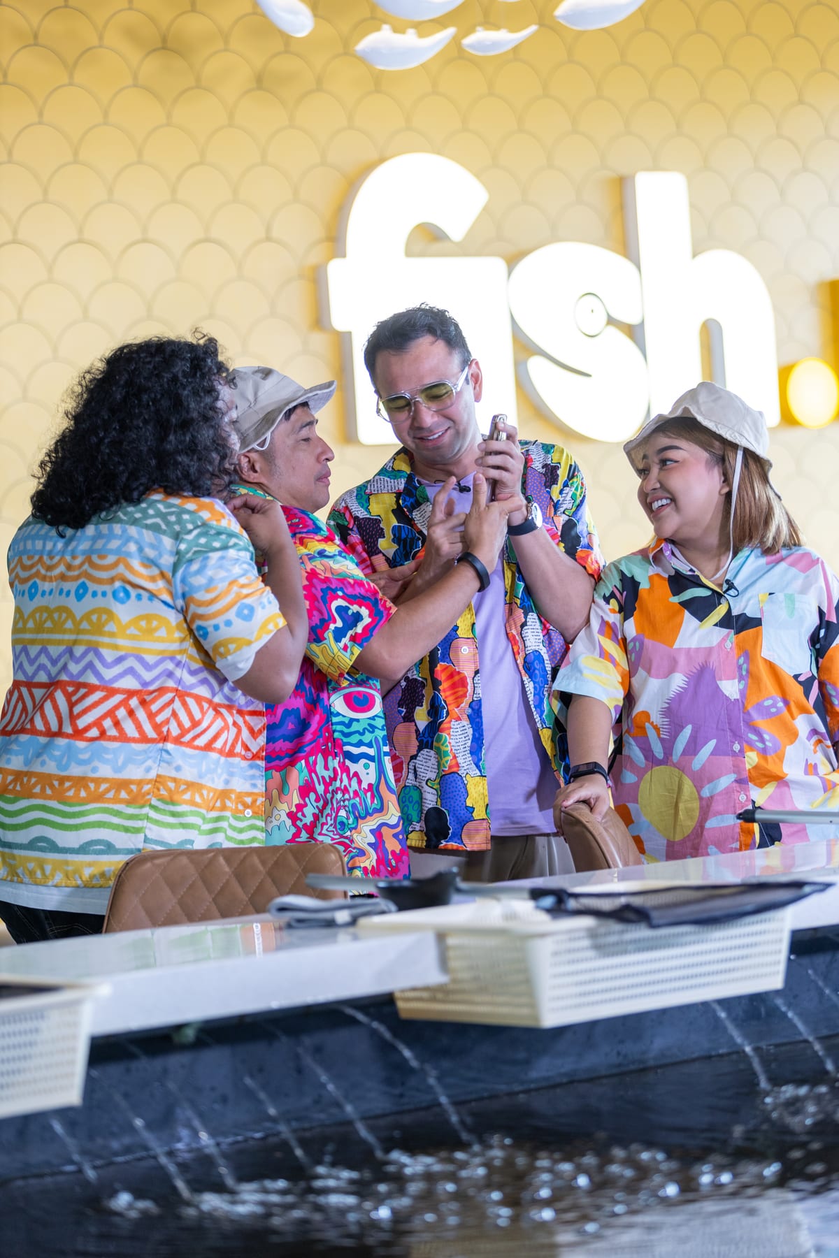 A group in matching printed shirts celebrating a catch at Fish.inc