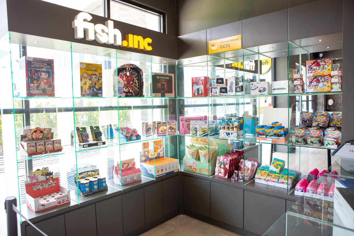 The lit prize cabinet at Fish.inc, stocked with consoles, speakers and collectables
