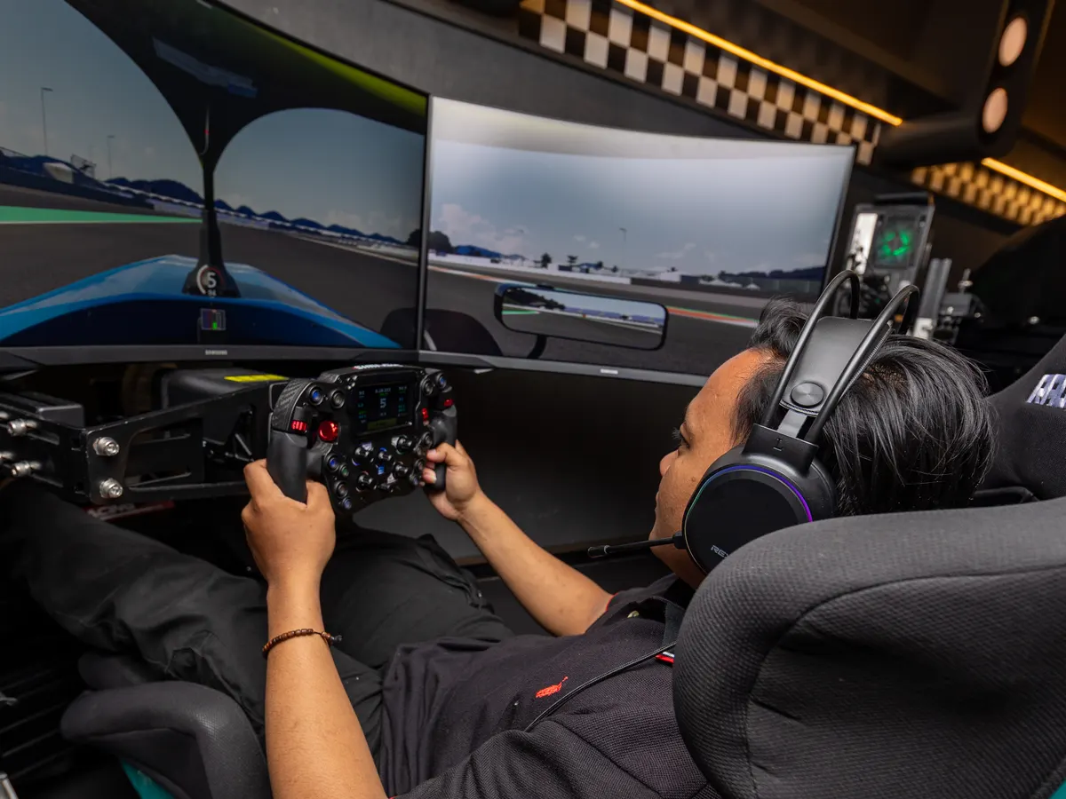 A driver at Race.inc holding the wheel, headset on, eyes on the centre screen