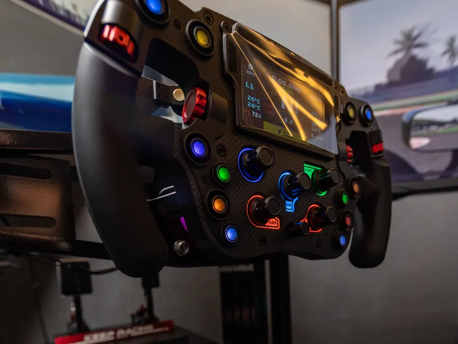 Close-up of a direct-drive wheel, its dash lit up in the dark