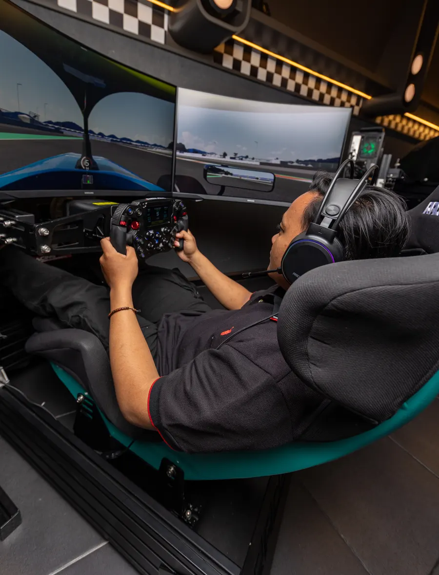 A driver reclined in the bucket seat at Race.inc, both hands on the wheel